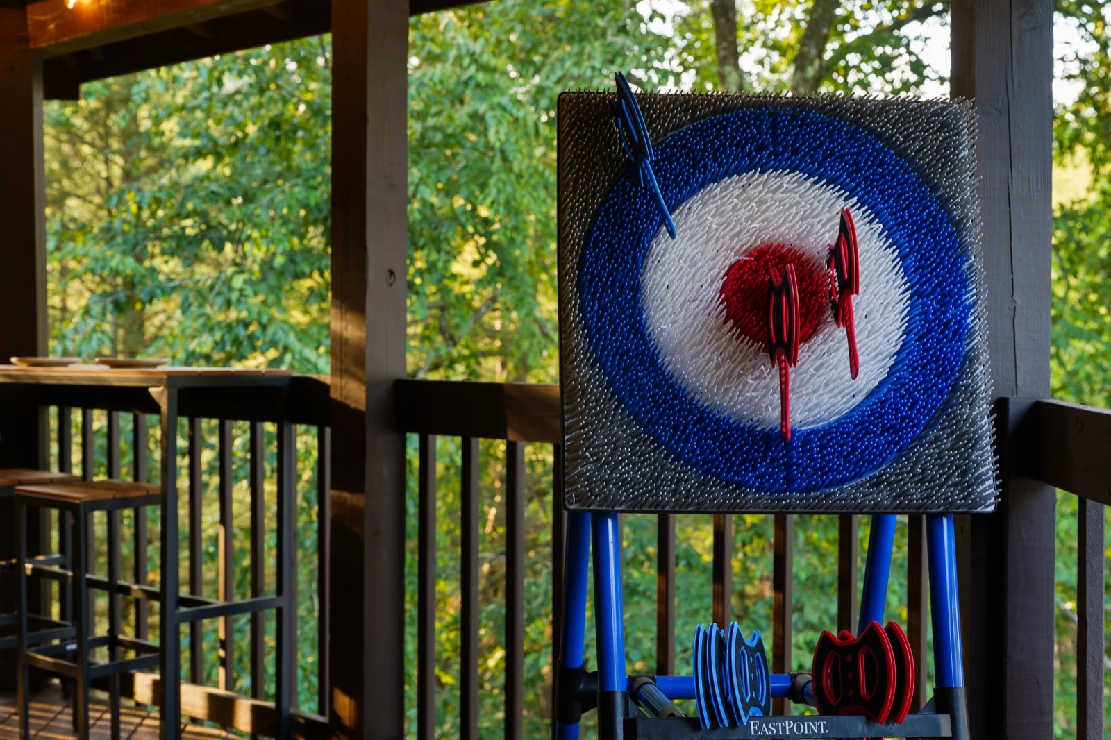 Axe-throwing target with red and blue game axes on the covered deck